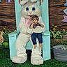 child, toddler, person, mascot, easter_bunny, costume, chair, grass, flowers, decorations, easter_eggs, bucket, wood_background, indoor, holiday, spring, cute, festival, celebration, portrait