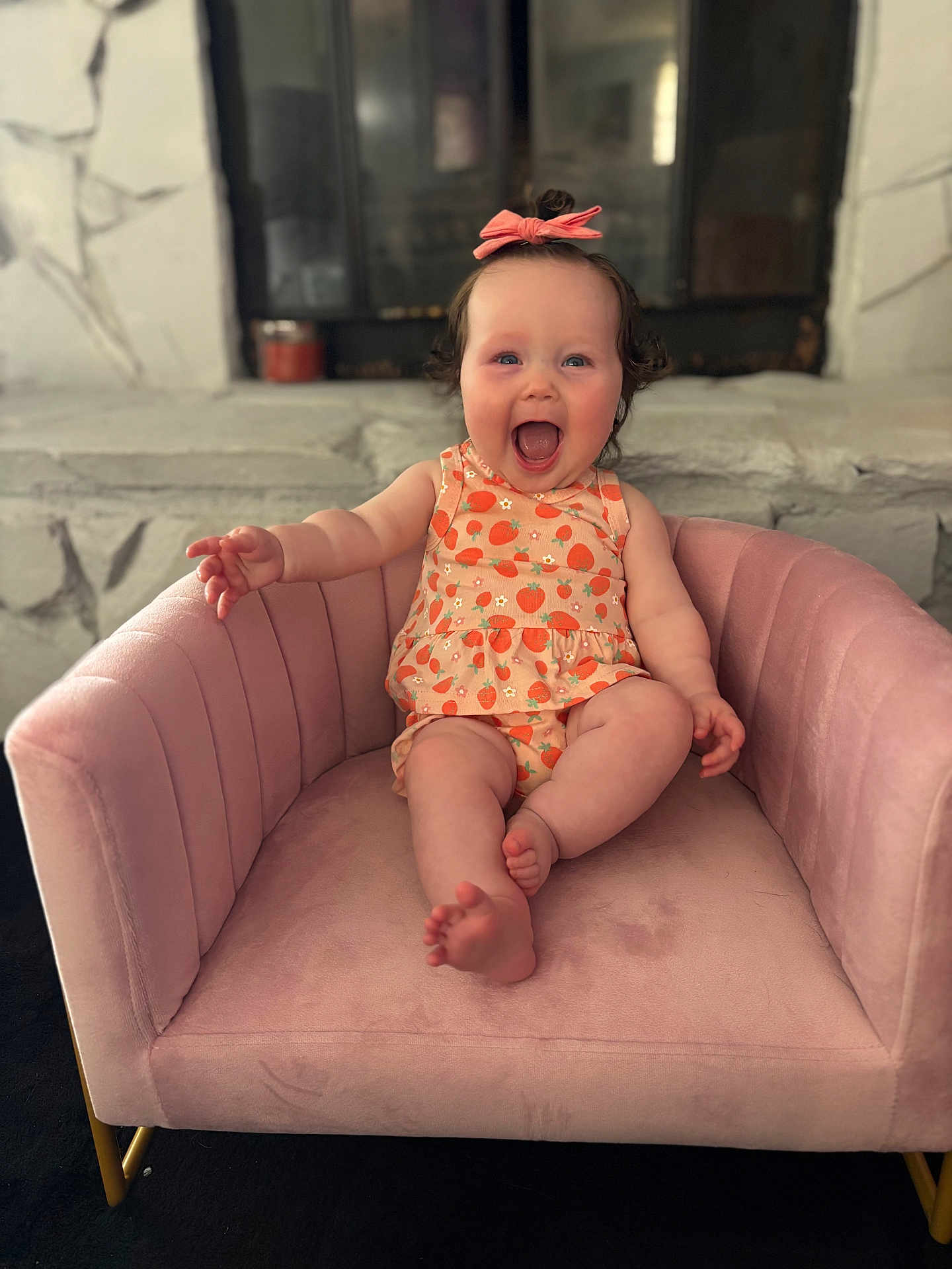 Trinity joined the competition — help win amazing prizes! baby, child, pink_bow, strawberry_pattern, pink_chair, smiling, happy, indoor, plush_chair, cute, sitting, person, infant, toddler, clothing, fun, joy, small_person, armchair, reaching_out