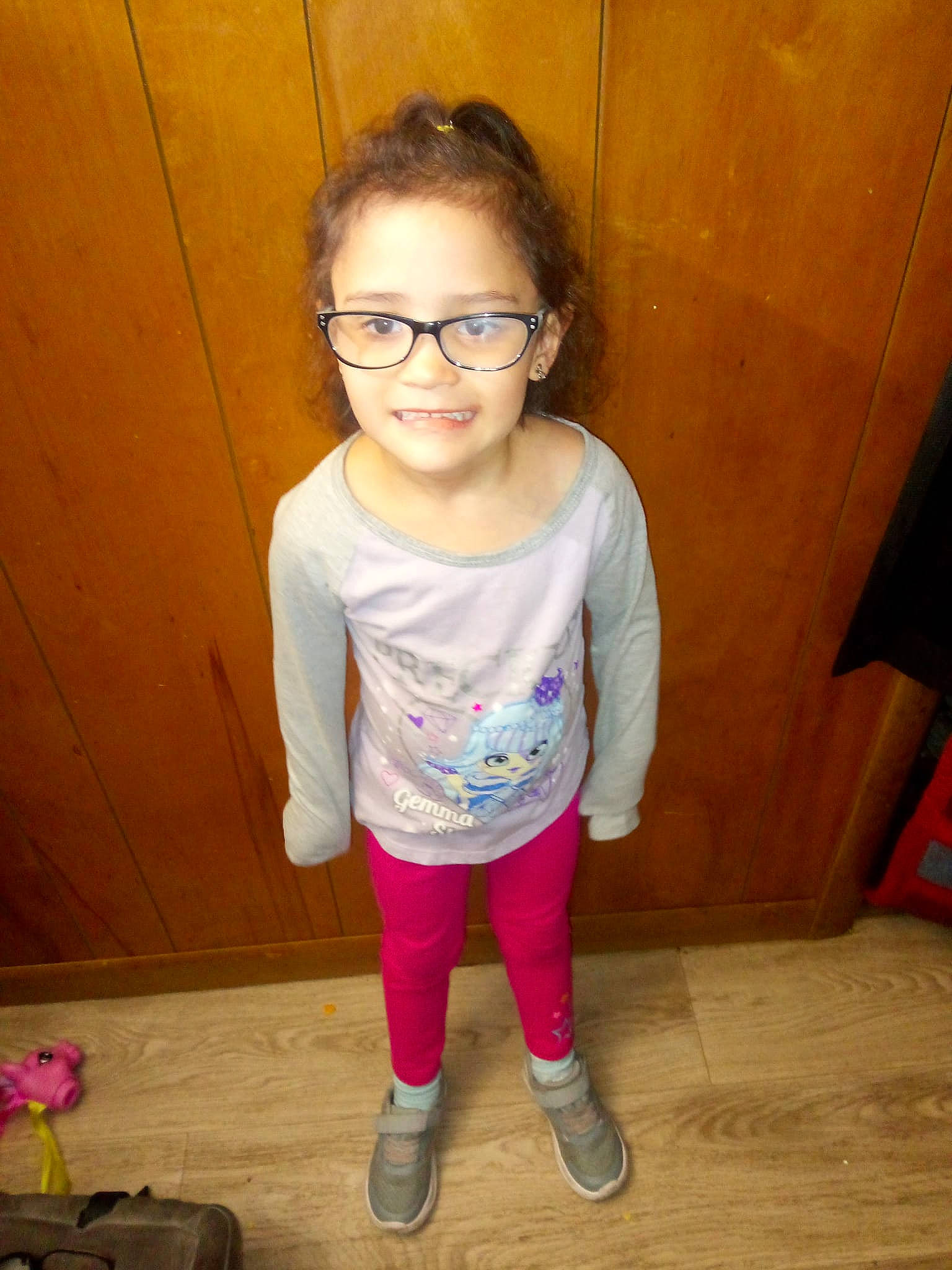 Makayla is registered to the contest to win money with this photo: baby_toddler_clothing, eyewear, flooring, fun, glasses, happy, hardwood, head, human_body, human_leg, joy, knee, long_hair, person, sleeve, smile, sock, t_shirt, thigh, toddler