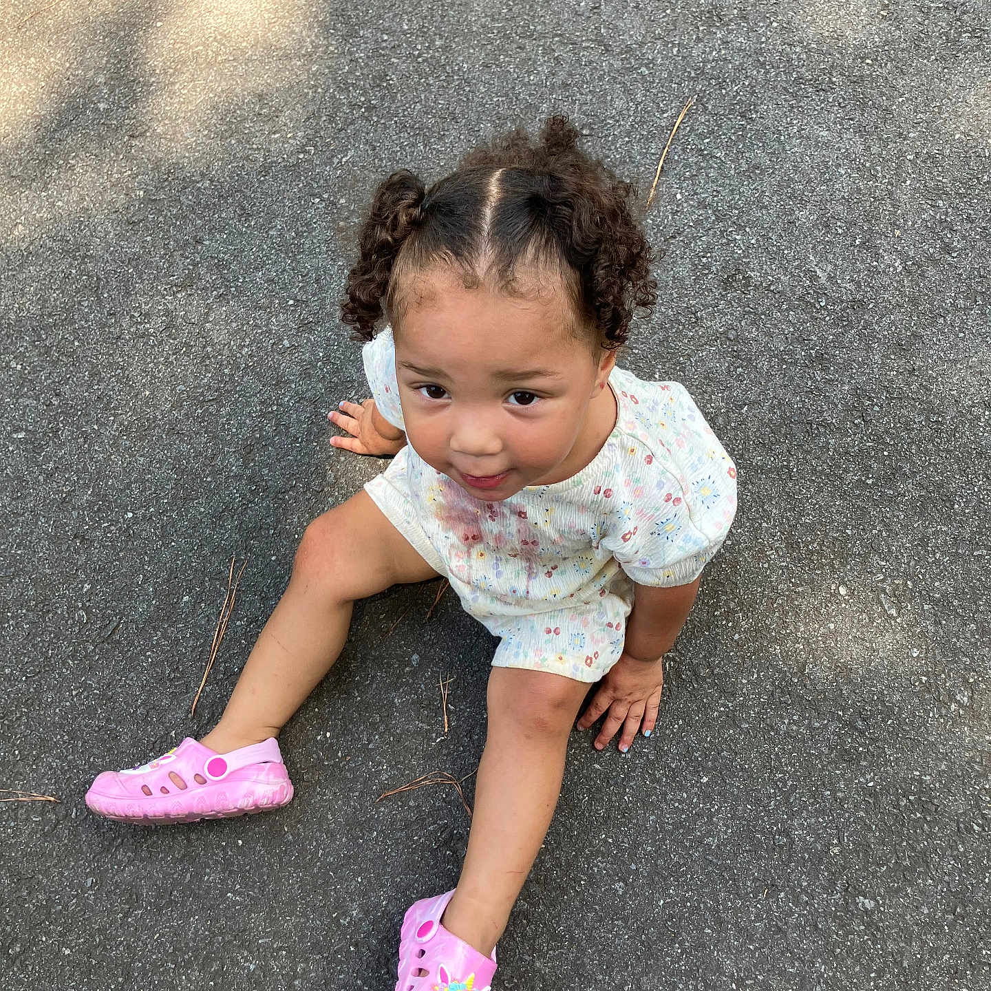 Tanylah is registered to the contest to win money with this photo: asphalt, casual_clothing, child, curious, curly_hair, cute, daylight, footwear, outdoor, pavement, person, pigtails, pink_shoes, playful, shadow, sitting, summer, toddler, unicorn, young