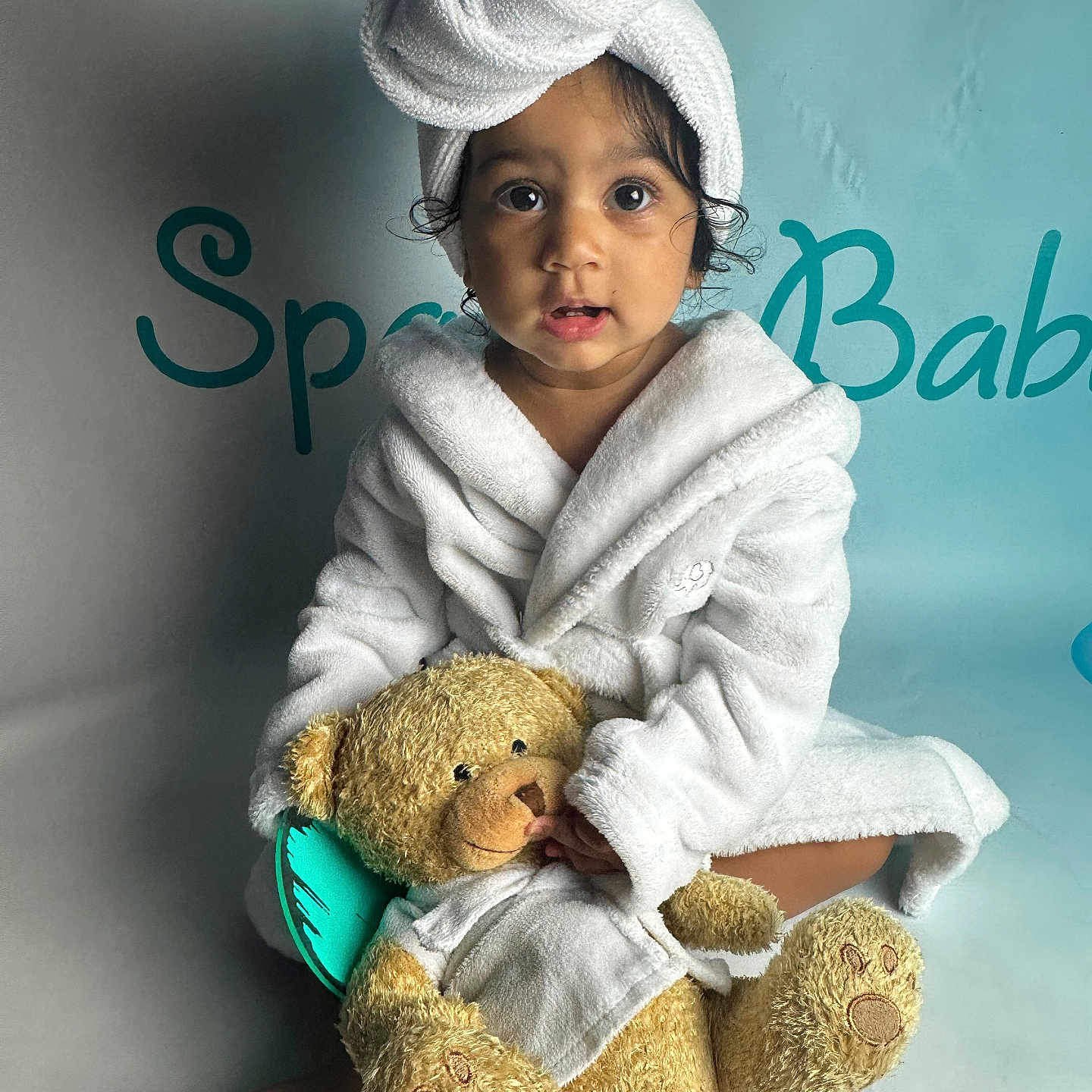 Anaiya is registered to the contest to win money with this photo: baby, beachwear, bonnet, cap, clothing, dress, face, fashion, hat, head, hood, person, photography, portrait, robe, sitting, spa, teddybear, towel, toy