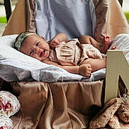 Maybel is registered to the contest to win money with this photo: baby, smiling, headband, basket, cushion, plush_toy, bunny, flowers, pink, soft_fabric, portrait, indoor, cute, child, decor, toy, happy, infant, cozy, photography