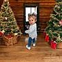 Solyanna a rejoint le concours — aidez-le/la à gagner de superbes lots ! blue_jeans, celebration, child, christmas_tree, curly_hair, cute, decorated_tree, festive, gifts, gray_sweater, holiday, holiday_decorations, indoor, person, purple_bows, smiling, toddler, white_shoes, wooden_floor, wooden_wall