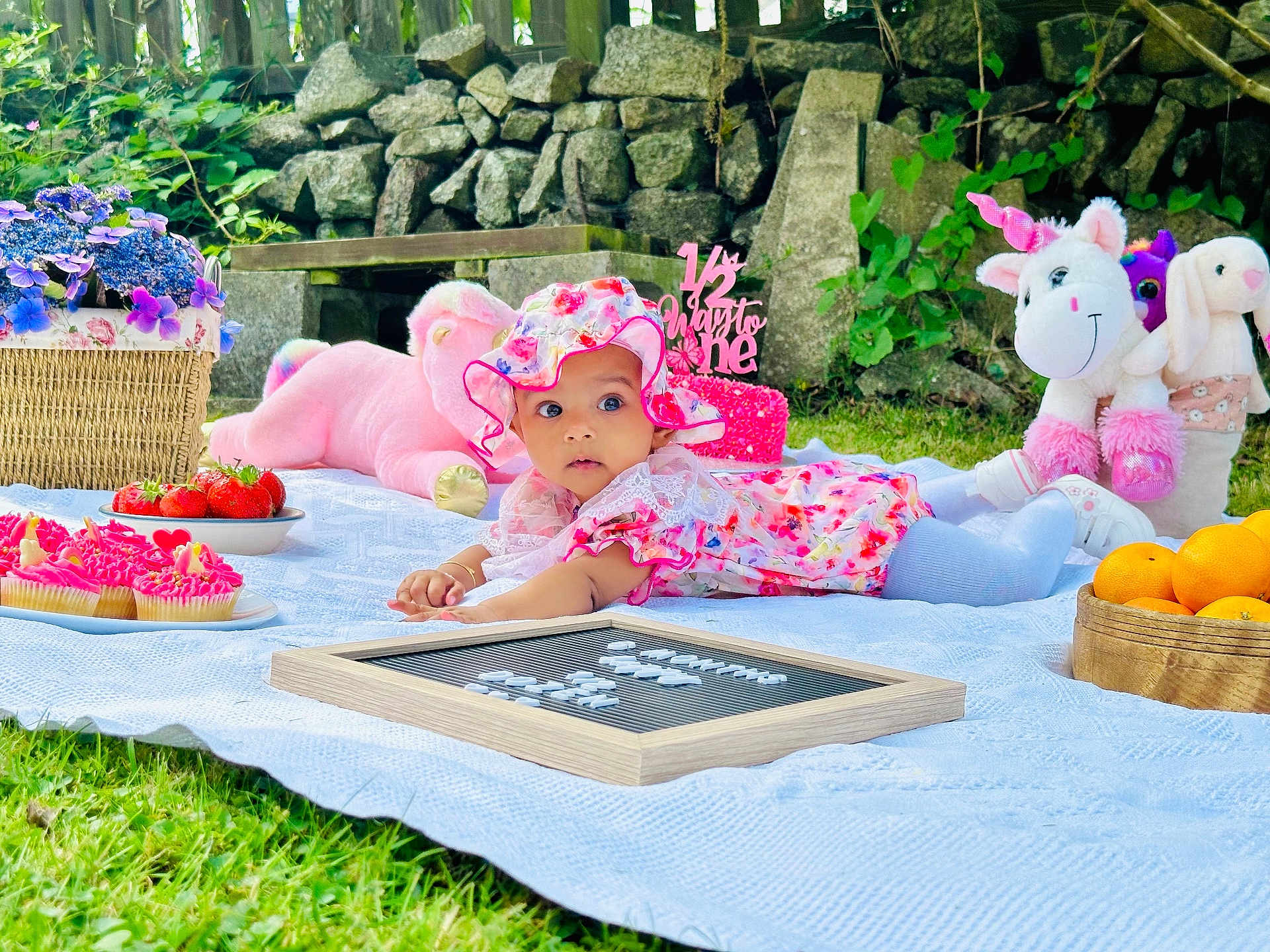Diveinya joined the competition — help win amazing prizes! baby, floral_hat, floral_dress, blanket, grass, cupcakes, strawberries, oranges, stuffed_animals, unicorn, pink_teddy_bear, basket, outdoor, garden, stone_wall, greenery, child, picnic, toy, cute
