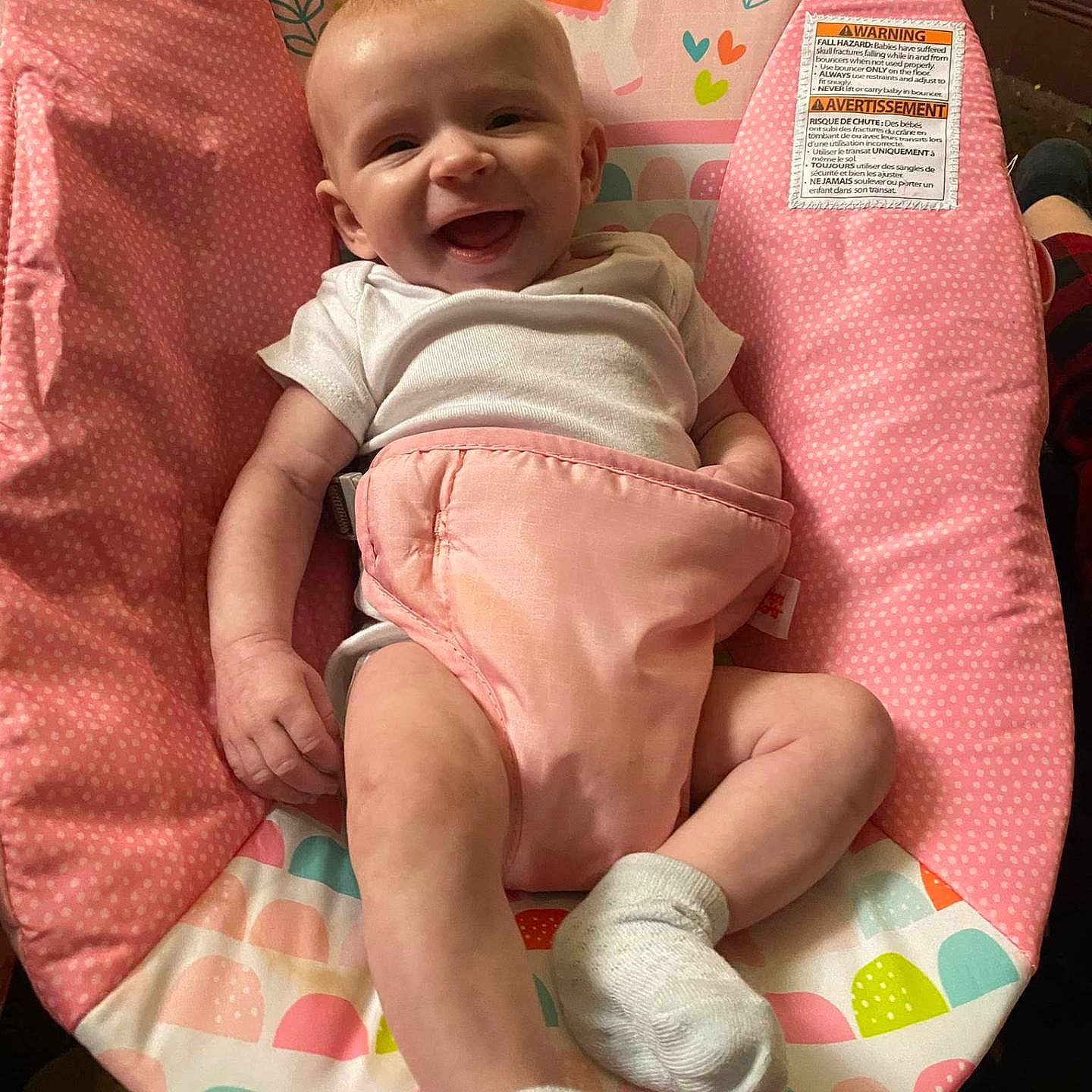 Lakelynn Lawrence joined the competition — help win amazing prizes! baby, bouncer_seat, bright_colors, cute, face, floral_design, hand, happy, indoors, infant, legs, onesie, patterned_fabric, pink, portrait, smiling, soft_fabric, sticker, warning_label, white_sock