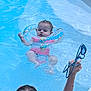 baby, child, swimming_pool, water, float, inflatable_ring, pink_swimsuit, goggles, adult_hand, blue_water, summer, outdoor, playing, fun, relaxing, splash, person, head, skin, floating