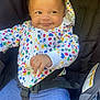 baby, child, car_seat, seatbelt, hoodie, colorful_clothing, blue_pants, smile, face, hand, infant, cute, indoor, portrait, sitting, playful, expression, young_child, people, clothing