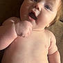 Elianna is registered to the contest to win money with this photo: baby, infant, child, skin, face, hand, diaper, expression, surprised, cute, chubby, lying_down, closeup, indoor, natural_light, person, human, soft_texture, brown_background, young