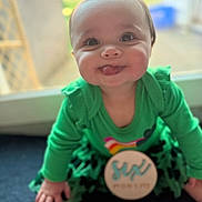 Bella is registered to the contest to win money with this photo: baby, bokeh, cheeks, child, closeup, eyes, feet, green_clothing, hands, happiness, indoor, infant, milestone_badge, onesie, portrait, sitting, six_months, smiling, tongue_out, window_light