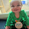 baby, bokeh, cheeks, child, closeup, eyes, feet, green_clothing, hands, happiness, indoor, infant, milestone_badge, onesie, portrait, sitting, six_months, smiling, tongue_out, window_light