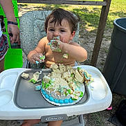Justin joined the competition — help win amazing prizes! baby, birthday, cake, celebration, child, dirt, face, food, foot, frosting, fun, grass, hand, high_chair, messy, outdoor, person, plate, seat, summer