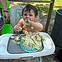 baby, birthday, cake, celebration, child, dirt, face, food, foot, frosting, fun, grass, hand, high_chair, messy, outdoor, person, plate, seat, summer