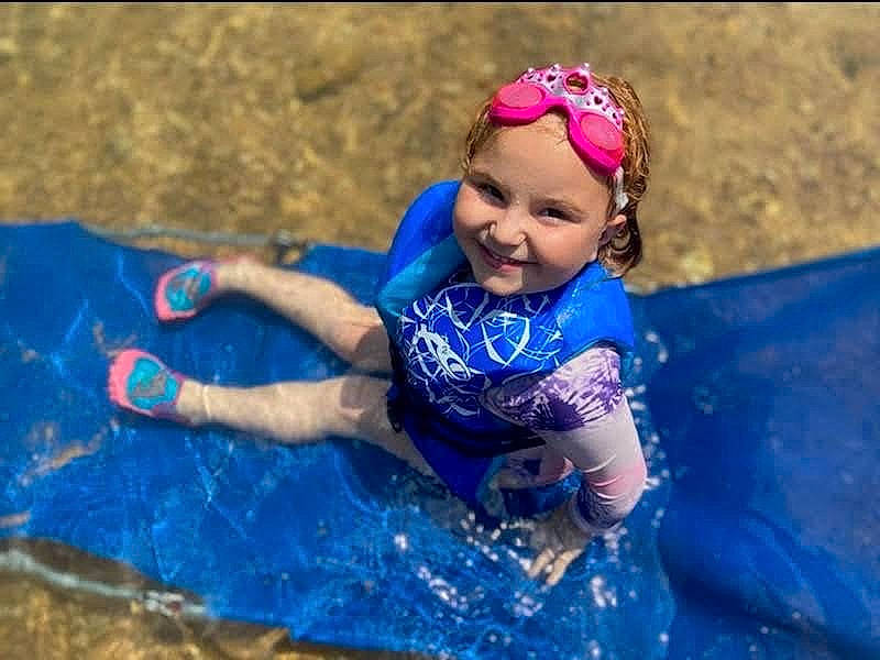 Charlee is registered to the contest to win money with this photo: bathing, child, competition_event, electric_blue, fun, games, grass, happy, headwear, inflatable, joy, laugh, leisure, people_in_nature, person, personal_protective_equipment, play, recreation, smile, sports