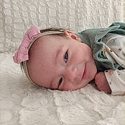 Violette a rejoint le concours — aidez-le/la à gagner de superbes lots ! baby, infant, smile, headband, bow, blanket, soft_texture, lying_down, cute, sleepy_eyes, green_outfit, closeup, face, skin, child, adorable, cozy, comfort, indoors, portrait