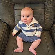 Malakhi is registered to the contest to win money with this photo: baby, child, infant, blue_eyes, striped_shirt, polo_shirt, shorts, smile, sitting, leather_chair, furniture, indoor, cute, portrait, person, human, young, skin, legs, feet