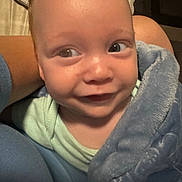 Sebastian is registered to the contest to win money with this photo: baby, blanket, blue, closeup, comfort, cozy, cuddle, expression, eyes, face, head, indoors, infant, person, portrait, skin, smile, soft, warm, young_child