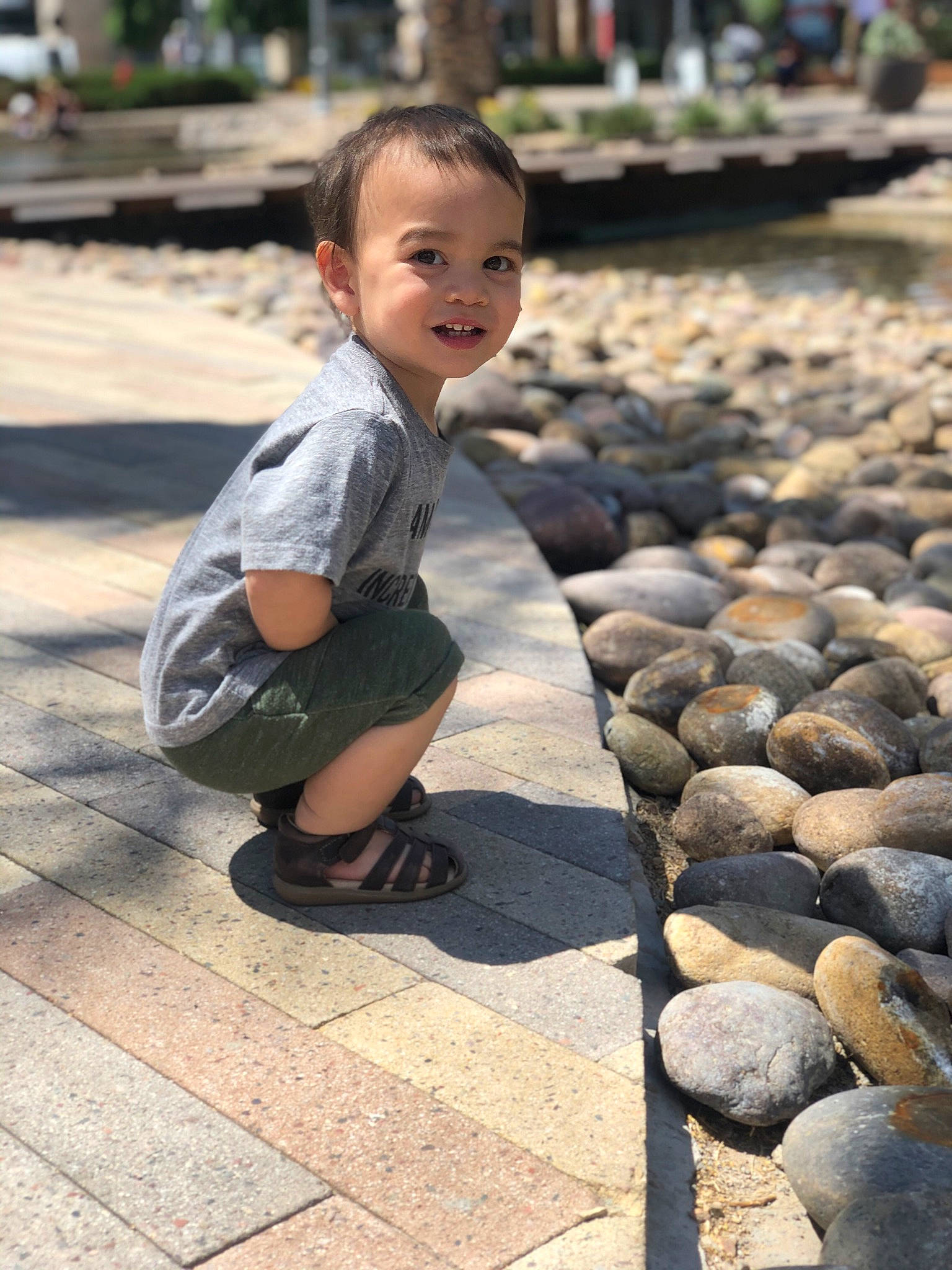 Rhett is registered to the contest to win money with this photo: child, cobblestone, flooring, fun, grass, happy, human, joy, leisure, people, person, photograph, public_space, road_surface, sitting, smile, snapshot, street, temple, toddler