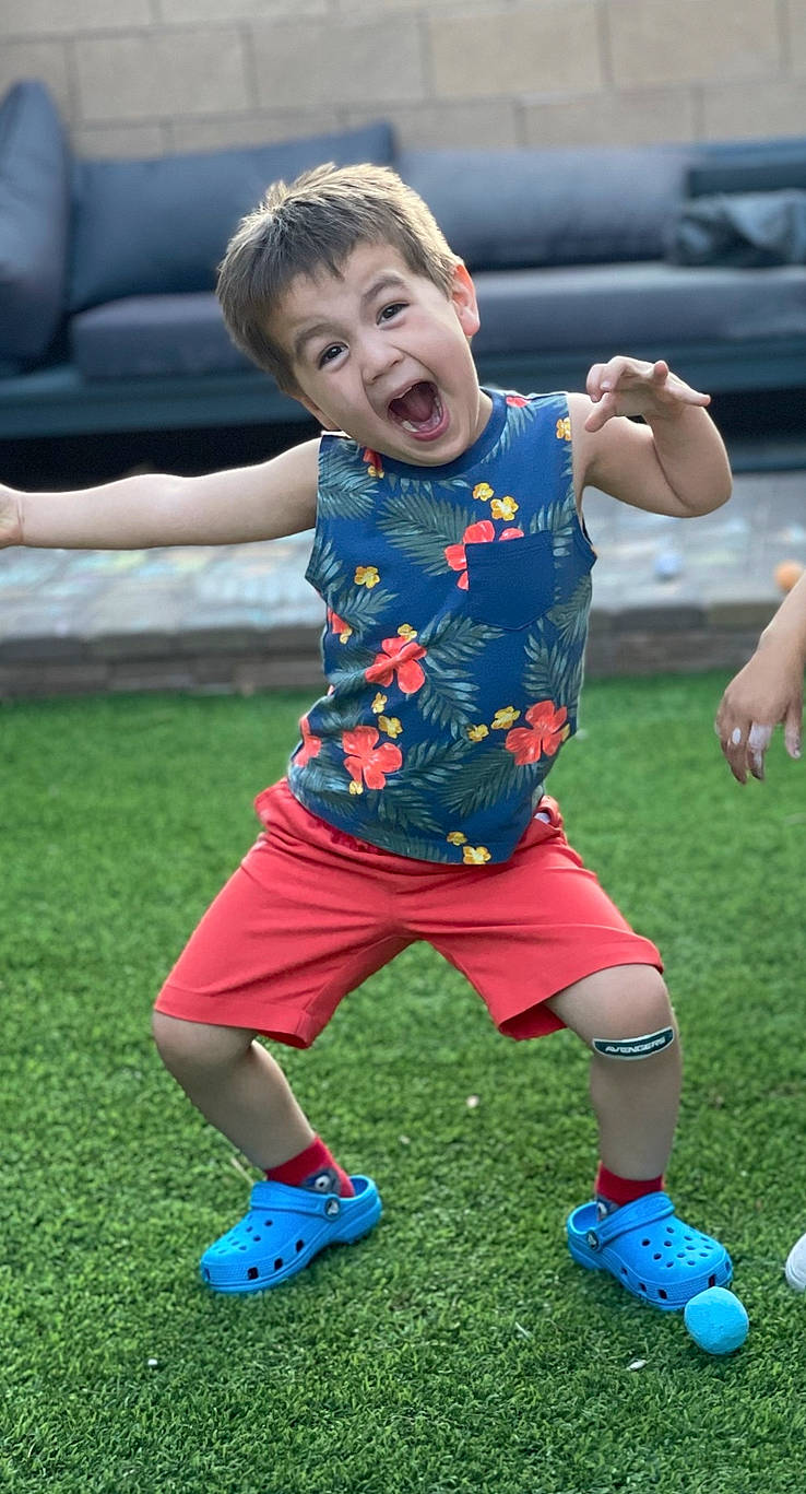 Joshua Jr. is registered to the contest to win money with this photo: ball, blue, facial_expression, fun, gesture, grass, happy, lawn, leisure, people, people_in_nature, person, plant, recreation, shorts, smile, sneakers, sports_equipment, summer, surprise