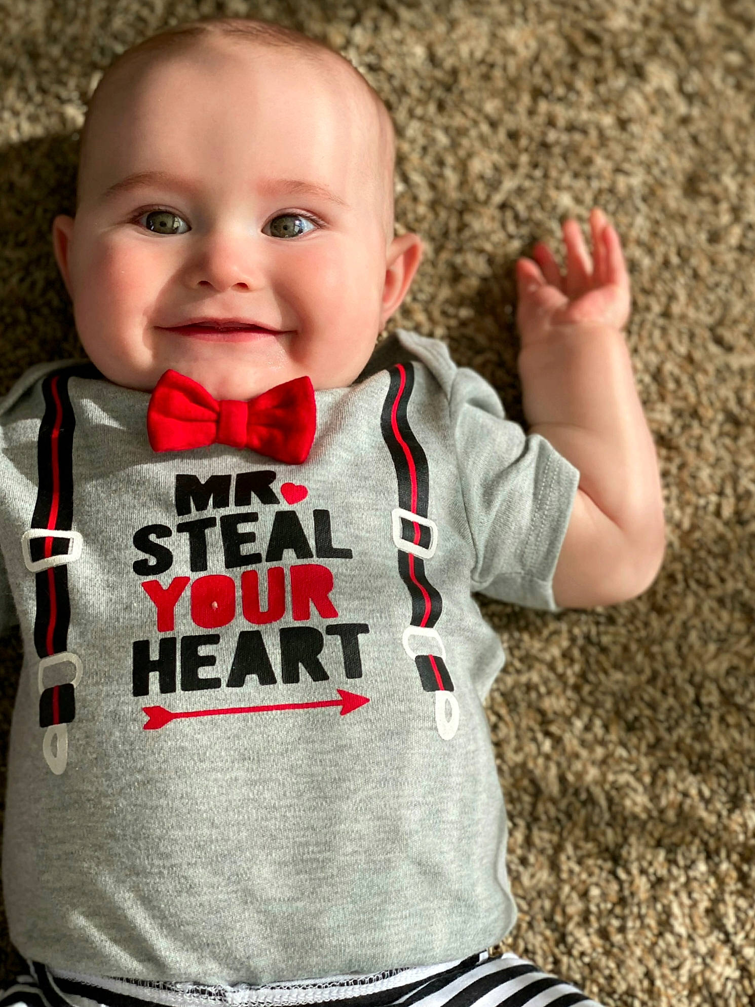 Lennon is registered to the contest to win money with this photo: baby, baby_products, baby_toddler_clothing, cheek, child, facial_expression, finger, gesture, hand, lip, mouth, outerwear, person, play, product, red, sleeve, smile, t_shirt, toddler