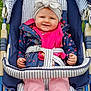 Judith participe au concours pour gagner de l'argent avec cette photo : baby, child, stroller, jacket, headband, pink_pants, smiling, outdoor, polka_dot, seatbelt, striped, clothing, person, cute, happy, infant, sitting, hands, face, headwear