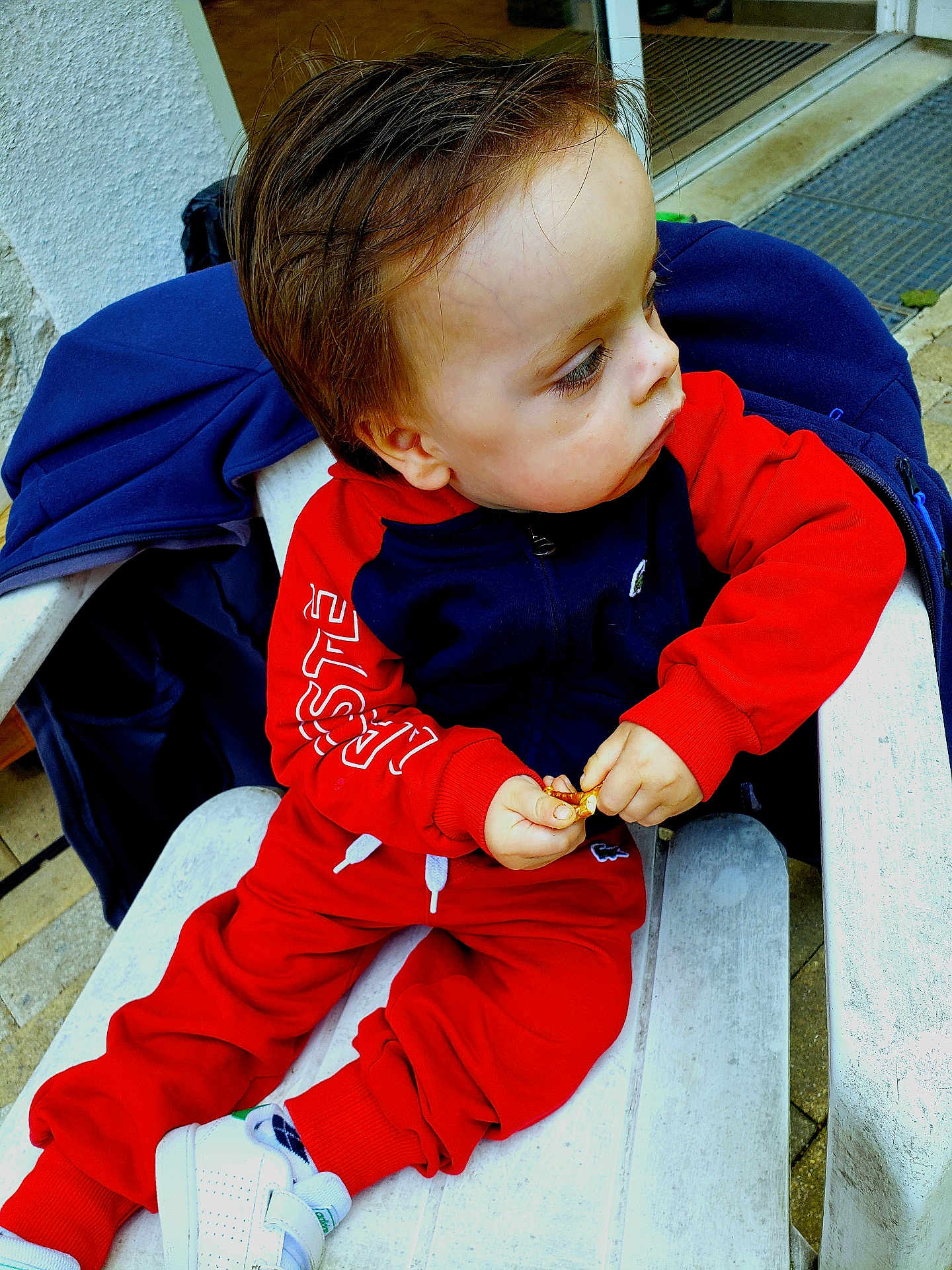 Gabryell participe au concours pour gagner de l'argent avec cette photo : casual, chair, child, doorway, face, floor, focused, hair, hand, jacket, navy_clothing, outdoor, portrait, red_clothing, sitting, snack, toddler, white_shoes, window, young_child