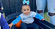 Charleigh is registered to the contest to win money with this photo: baby, child, smiling, outdoor, pumpkin, wagon, autumn, blue_bow, infant, portrait, family, playful, sitting, grass, fence, adults, clothing, sneakers, fall, harvest