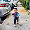 Charleigh is registered to the contest to win money with this photo: toddler, child, smiling, outdoor, sidewalk, walking, denim_jacket, pink_shirt, pants, sneakers, curly_hair, parked_cars, parking_lot, residential, apartment, palm_tree, hedges, concrete, portrait, happy