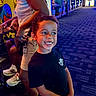 Cameron joined the competition — help win amazing prizes! child, smiling, portrait, indoor, arcade, entertainment, game_machines, neon_lighting, carpet, adult, family, black_shirt, curly_hair, happy, standing, playground, colorful, background, recreation, photography