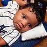 adorable, baby, bed, blanket, blue, child, closeup, curly_hair, eyes, face, indoor, infant, lying_down, photography, pillow, portrait, shirt, striped_clothing, white, wooden_floor
