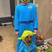 Luna joined the competition — help win amazing prizes! man, dog, costume, alien, blue_outfit, green_headpiece, indoor, tile_floor, toys, basket, smiling, pet, matching_outfits, funny, portrait, headwear, animal, home, cute, three_eyes