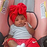 baby, infant, child, car_seat, pink, red_bow, red_shorts, white_shirt, white_socks, sitting, lying_down, portrait, indoors, face, eyes, hand, crossed_legs, smiling, clothing, photography