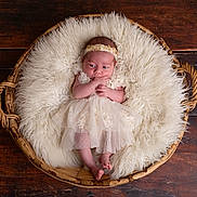Mia participe au concours pour gagner de l'argent avec cette photo : baby, infant, basket, fluffy_cushion, wooden_floor, headband, dress, newborn, sleepwear, portrait, indoors, cute, soft_texture, resting, small_feet, hands, curious, laying, child, cozy