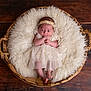 baby, infant, basket, fluffy_cushion, wooden_floor, headband, dress, newborn, sleepwear, portrait, indoors, cute, soft_texture, resting, small_feet, hands, curious, laying, child, cozy