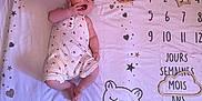 Mia a rejoint le concours — aidez-le/la à gagner de superbes lots ! baby, child, infant, romper, milestone_blanket, floor, wood_floor, heart, star, cat_illustration, hand, face, eyes, fingers, clothing, cute, lying_down, pink, decor, playful