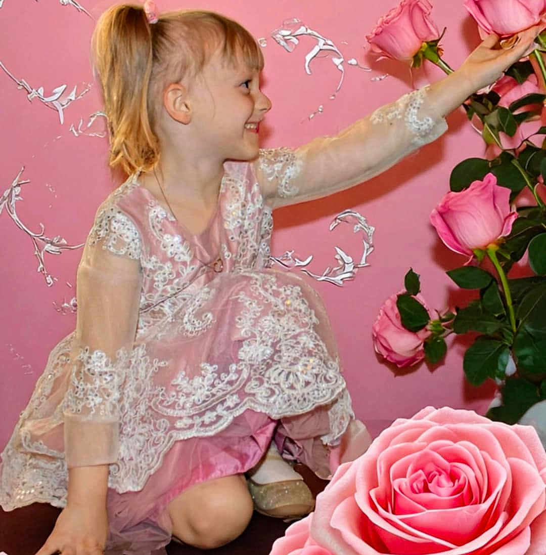 Amanda joined the competition — help win amazing prizes! child, girl, smiling, lace_dress, pink_dress, roses, flowers, pink_background, sitting, happy, portrait, flower_arrangement, green_leaves, indoor, cute, young_girl, kneeled, long_sleeves, fair_skin, blonde_hair