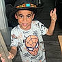 child, boy, cowboy_hat, spiderman, tshirt, shorts, shoes, kitchen, floor, wood, door, smiling, peace_sign, pose, indoor, person, playful, standing, happy, casual_clothing