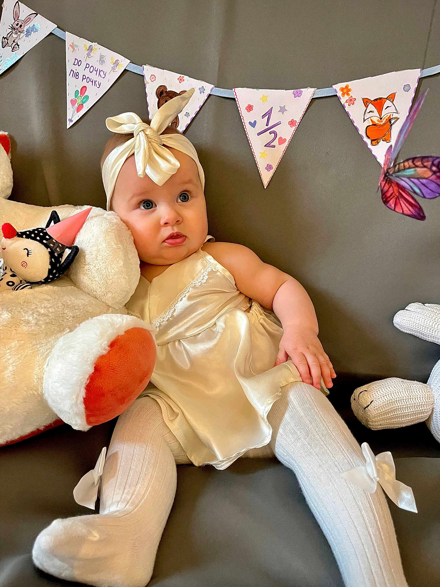 Miia a rejoint le concours — aidez-le/la à gagner de superbes lots ! baby, child, dress, headband, soft_toys, stuffed_animal, couch, decorations, banner, butterfly, white_tights, ribbon, celebration, indoor, portrait, cute, milestone, infant, happy, cozy