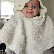 Thibault participe au concours pour gagner de l'argent avec cette photo : baby, child, hooded_poncho, white_clothing, smiling, blue_eyes, person_holding, gray_sweater, indoor, home_interior, window, natural_light, cute, warm_clothing, portrait, happy, infant, soft_texture, cozy, baby_fashion