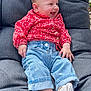baby, child, smiling, jeans, red_clothing, socks, cushion, chair, happy, cute, portrait, indoors, infant, casual_clothing, relaxed, seated, baby_girl, denim, buttoned_shirt, cozy