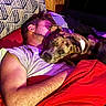Tyson joined the competition — help win amazing prizes! man, dog, bed, blanket, pillow, sleeping, cuddling, indoor, resting, human, pet, comfort, snuggling, red_blanket, casual_clothing, wooden_wall, mixed_breed_dog, portrait, relaxation, warm_lighting