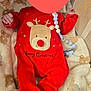 baby, blanket, child, christmas, clothing, comfort, cute, footed_pajamas, holiday, indoors, infant, newborn, pacifier_clip, plush_toy, red_onesie, reindeer, resting, sleeping_area, soft_texture, warm