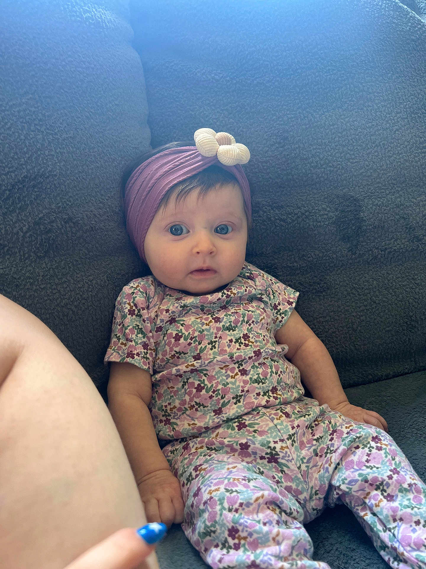 Valentina joined the competition — help win amazing prizes! baby, child, floral_outfit, headband, purple, bow, blue_eyes, couch, gray, hand, nail_paint, finger, seated, curious, indoor, person, young_child, comfort, soft_texture, casual