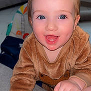 Austin-James is registered to the contest to win money with this photo: toddler, child, smiling, face, blue_eyes, sweater, fuzzy_clothing, hand, indoor, living_room, sofa, couch, toy, happy, person, closeup, baby, cute, skin, expression
