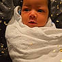 baby, newborn, infant, swaddled, towel, blanket, confetti, celebration, portrait, face, eyes, hair, cheeks, wrapped, cozy, indoor, soft_texture, photography, expression, closeup