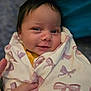 Kehlani joined the competition — help win amazing prizes! baby, newborn, swaddle, blanket, bow_pattern, smile, face, eyes, hair, hand, fingers, bedding, portrait, close_up, cozy, indoors, infant, soft_texture, parent_hand, happy