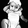 Jessalynn is registered to the contest to win money with this photo: arms, baby, black_and_white, bow, child, close_up, dark_background, eyes, face, headband, infant, knitwear, legs, onesie, photography, portrait, sitting, smiling, studio, wide_eyed