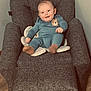 Hunter Jr is registered to the contest to win money with this photo: baby, child, smiling, blue_onesie, bear_patch, armchair, gray_furniture, cushion, indoor, wooden_floor, person, seated, happy, cute, infant, young_child, cozy, plush, portrait, casual