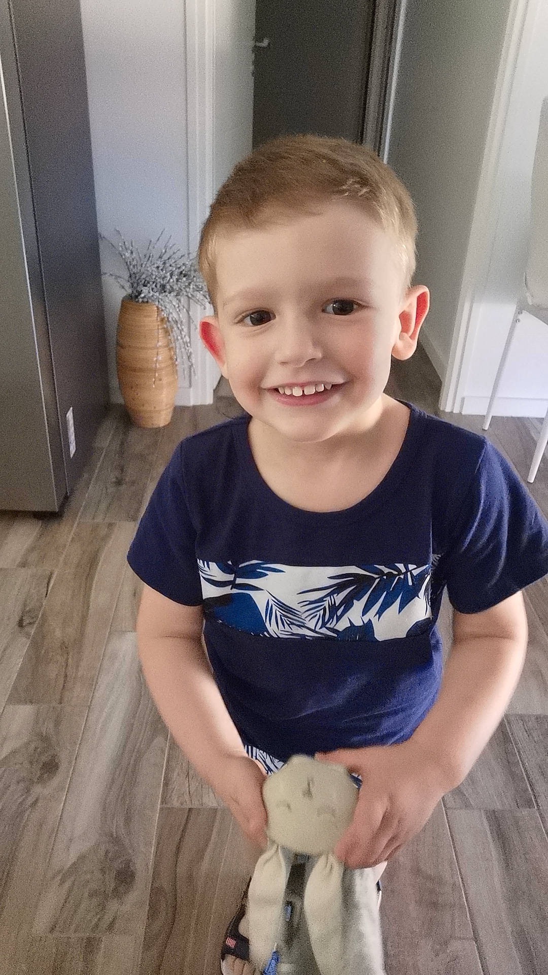 Alexis participe au concours pour gagner de l'argent avec cette photo : boy, casual, child, decoration, face, flooring, hair, happy, holding, home, indoor, open_door, person, shirt, short_sleeve, smile, standing, toy, vase, wood_floor