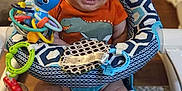 Wesley is registered to the contest to win money with this photo: baby, smiling, infant, baby_seat, toy, indoor, colorful, orange_shirt, dinosaur_print, feet, face, happy, child, window_blinds, cushion, plastic_toy, playful, person, sitting, cute