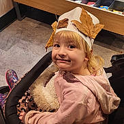 Sophia is registered to the contest to win money with this photo: autumn, blonde_hair, child, clothing, cute, face, floor, fridge, hat, indoor, juice_bottles, leaf_crown, pink_hoodie, plastic_cover, shopping, smile, store, stroller, toddler, water_bottles